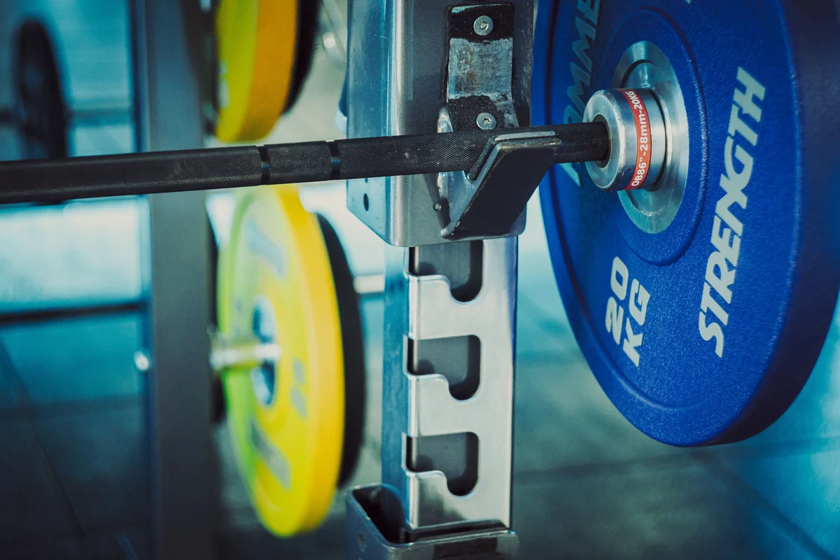 Twenty-kilo plates loaded on a barbell in a gym rack, the iron reality behind 150 kg