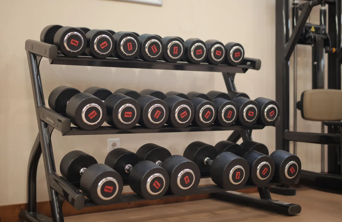 A row of heavy black and red dumbbells lined up on a gym rack, the hardware behind 200 lb