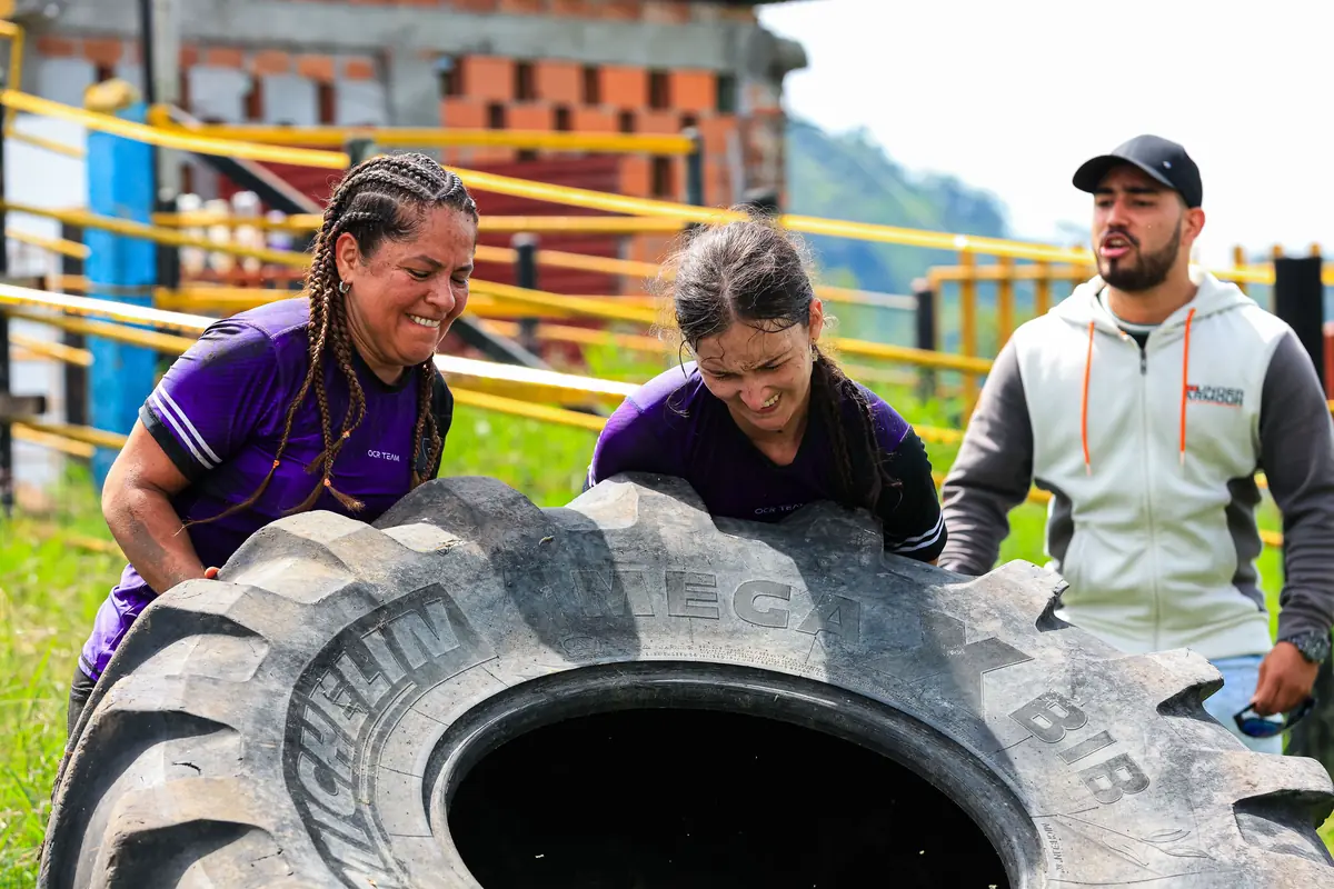 Two women and a man flipping a giant tyre in an outdoor fitness session, the full-body answer to 250 lb