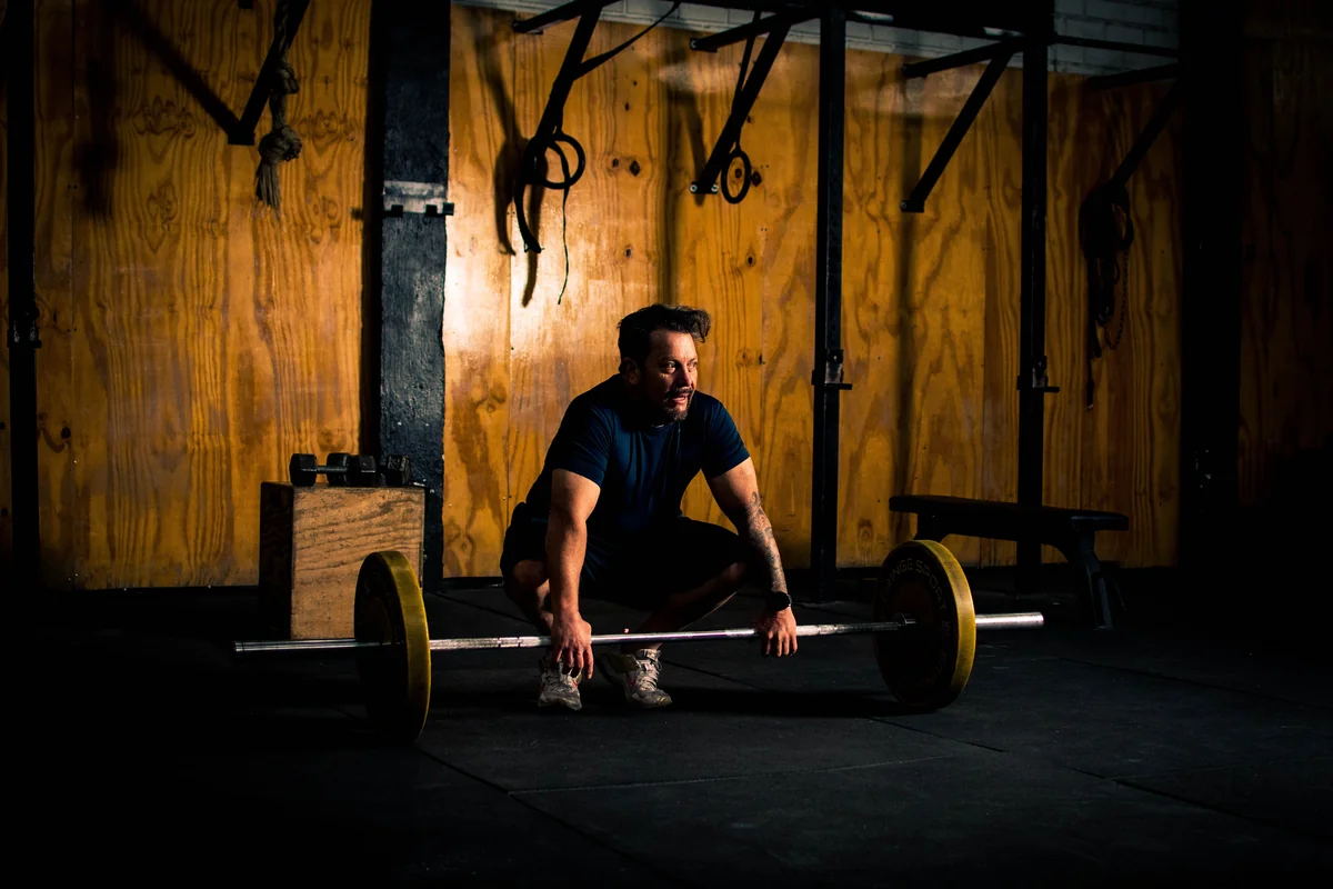 A lifter bracing to deadlift a heavily loaded barbell in a dark gym, the kind of session where 300 lb shows up on the plates