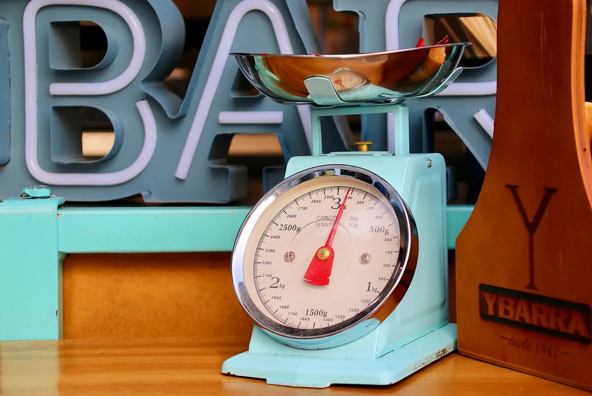 A vintage turquoise mechanical kitchen scale with a red needle, the charming old way to weigh in kilos